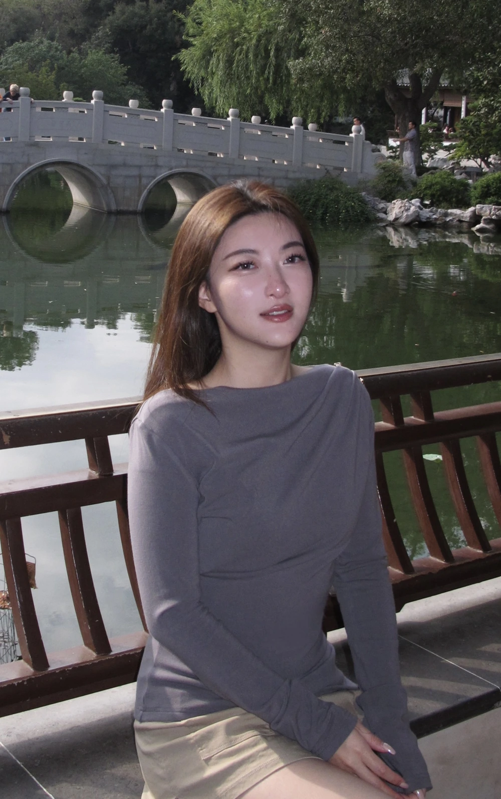 Kelly beside a garden pond and stone bridge